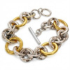 Náramek s řetězovým designem ve stříbrné a zlaté barvě, délka 210 mm, šířka 19 mm.
